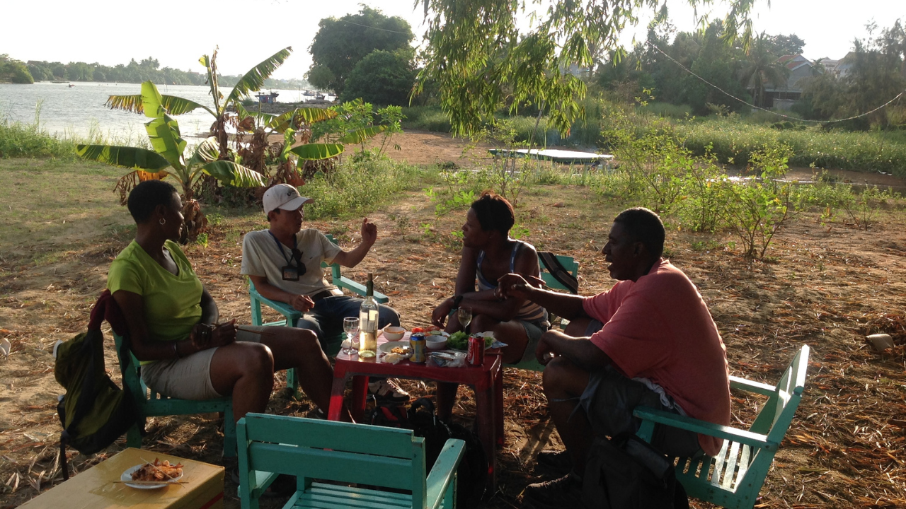 Black male and 2 Black females having dinner beside the Thu Bon River in Hoi An, Vietnam