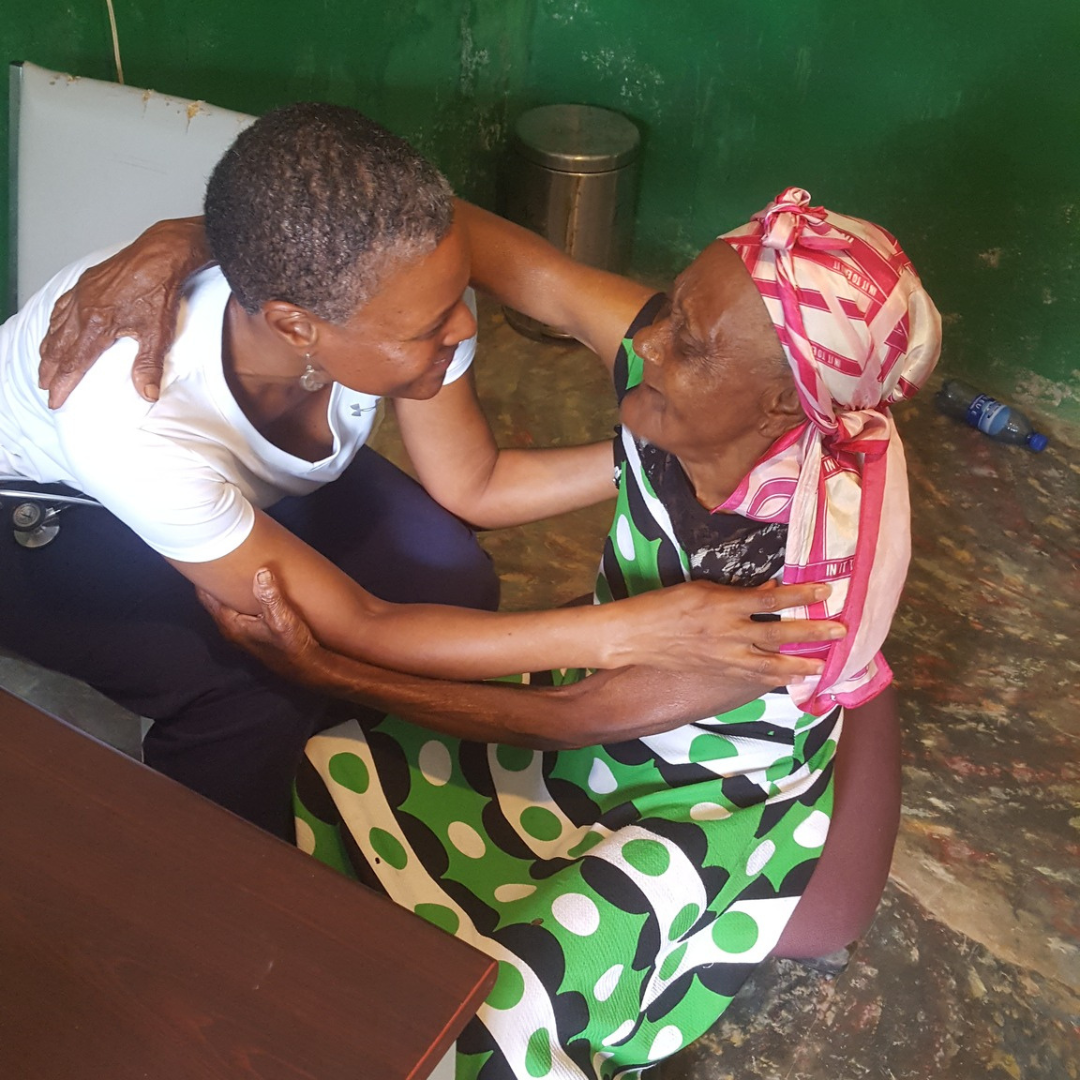 Black female doctor and an elderly Haitian woman hugging and chatting during a Medical Mission trip to Haiti.