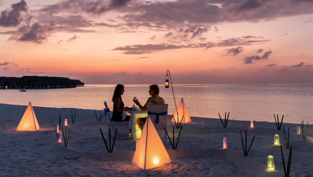 Couple on the beach at sunset having dinner