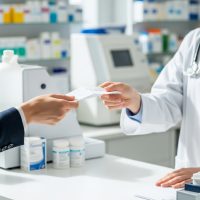 Someone handing a pharmacist a prescription
